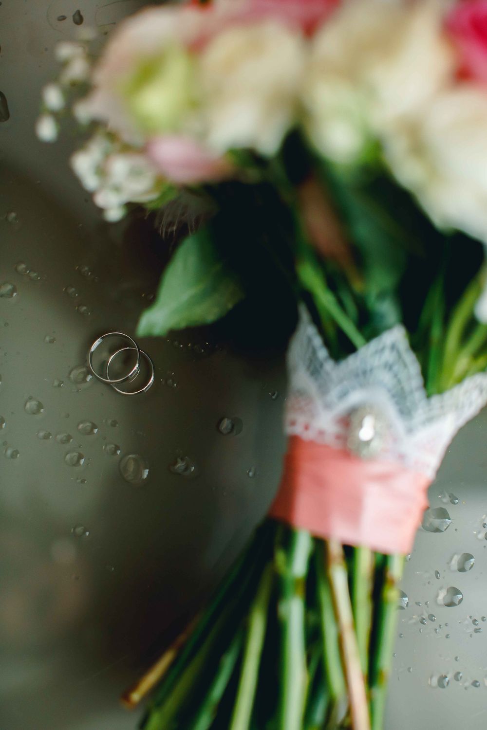 Fotografía de muestra: anillos junto a un ramo de flores sobre una superficie reflectante.