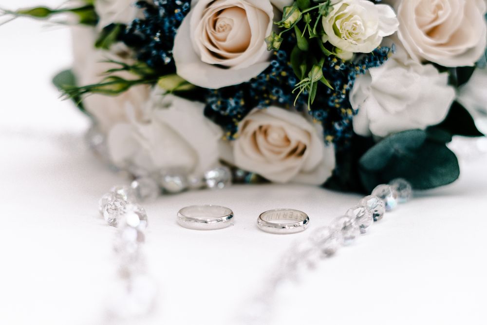 Fotografía de muestra: anillos de boda con un ramo y detalles decorativos.